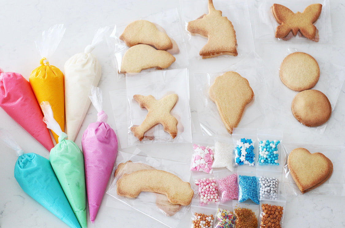 The Ultra-Mega DIY Cookie Kit - Includes 6 Piping bags, filled with ready to use icing in Blue, Purple, Pink, White, Yellow & Green. 10 Bags of sprinkles/decorations 20 Cookies, ready to decorate. Cookie shapes will include a mixed selection of all of our kits.