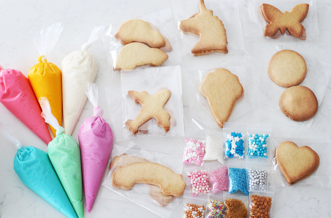 The Ultra-Mega DIY Cookie Kit - Includes 6 Piping bags, filled with ready to use icing in Blue, Purple, Pink, White, Yellow & Green.  10 Bags of sprinkles/decorations  20 Cookies, ready to decorate. Cookie shapes will include a mixed selection of all of our kits.